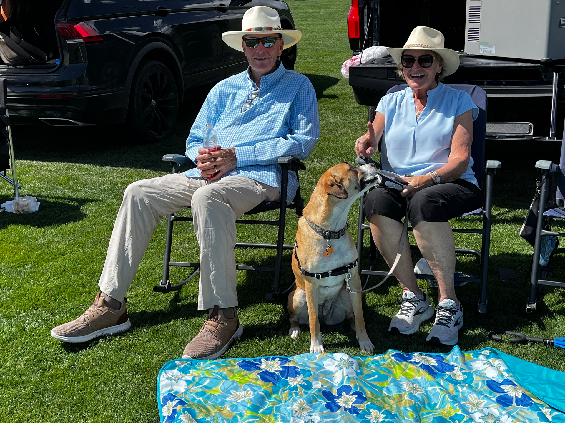 A man and a woman are sitting in chairs with a dog.