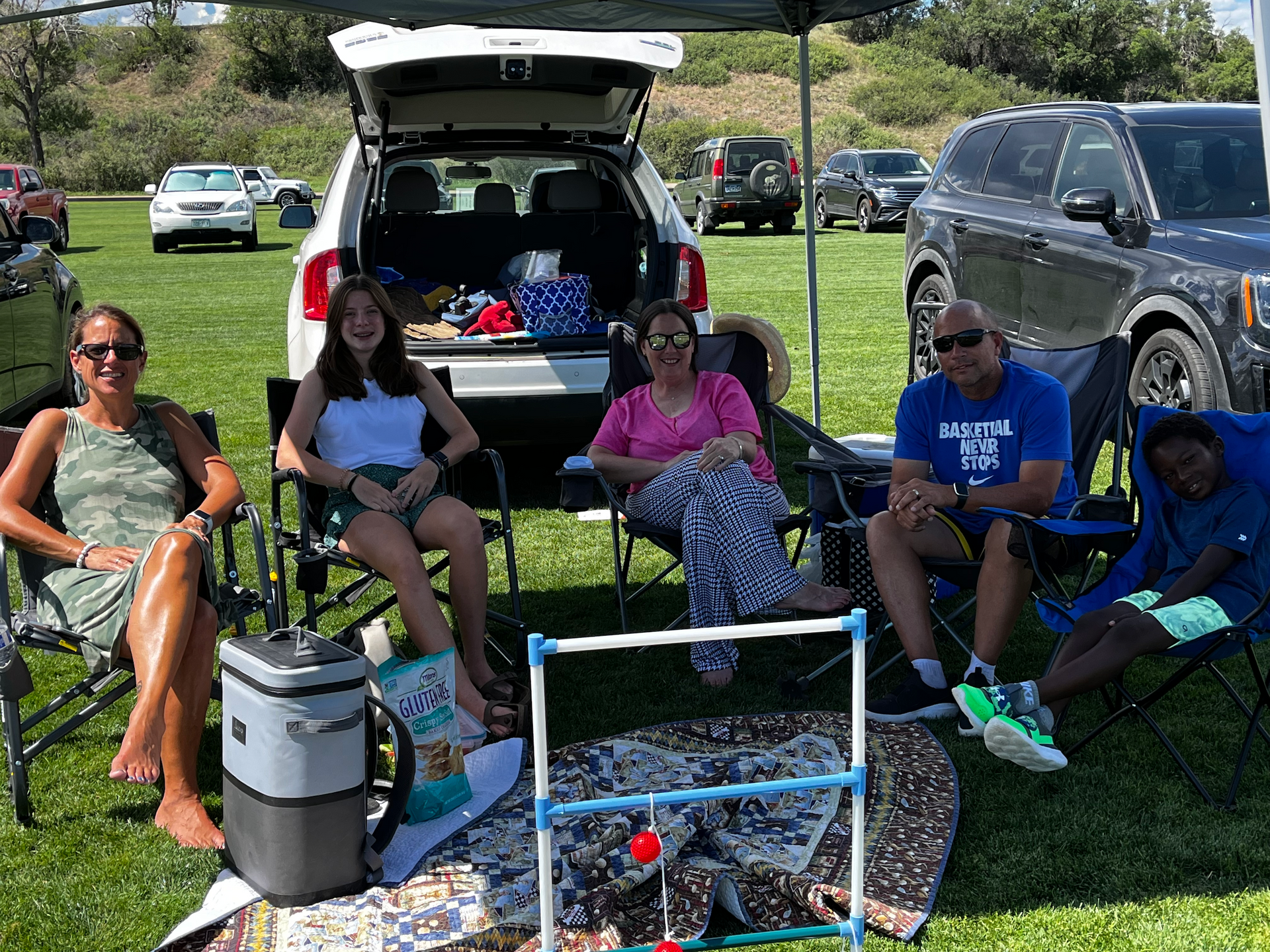 A group of people are sitting in chairs in front of a car.