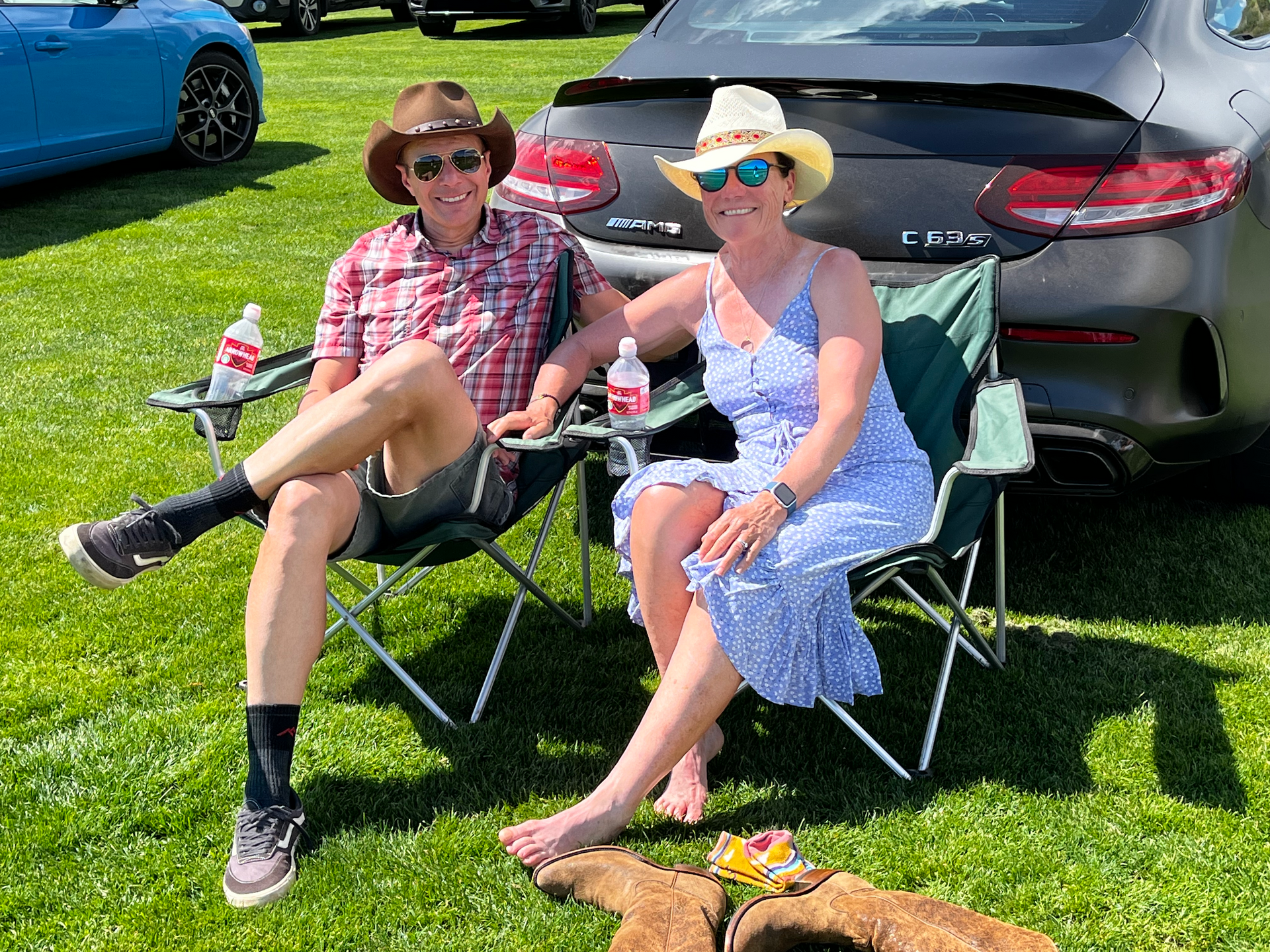 A man and a woman are sitting in chairs in front of a car.