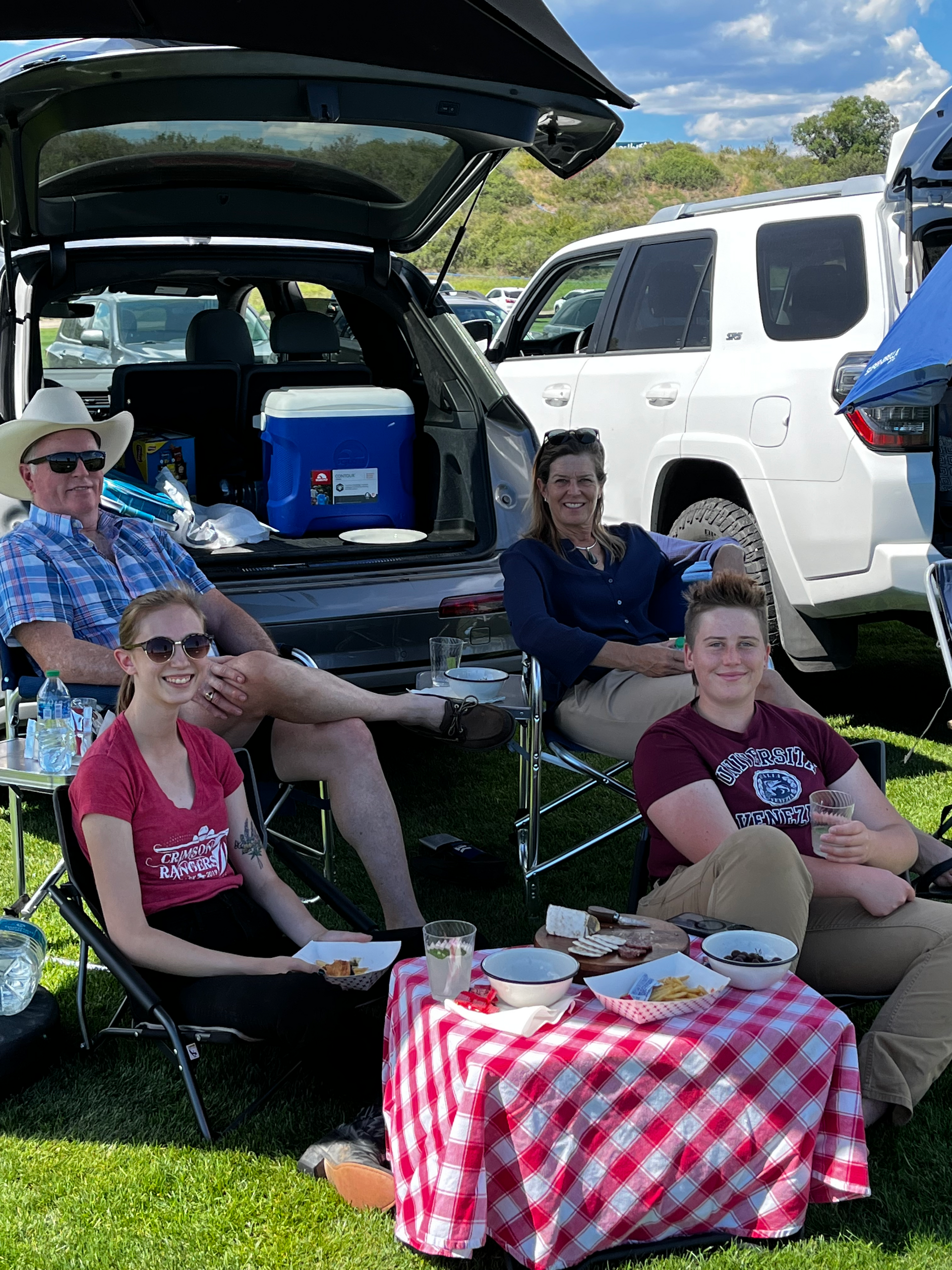 A group of people are sitting around a picnic table in the back of a truck.