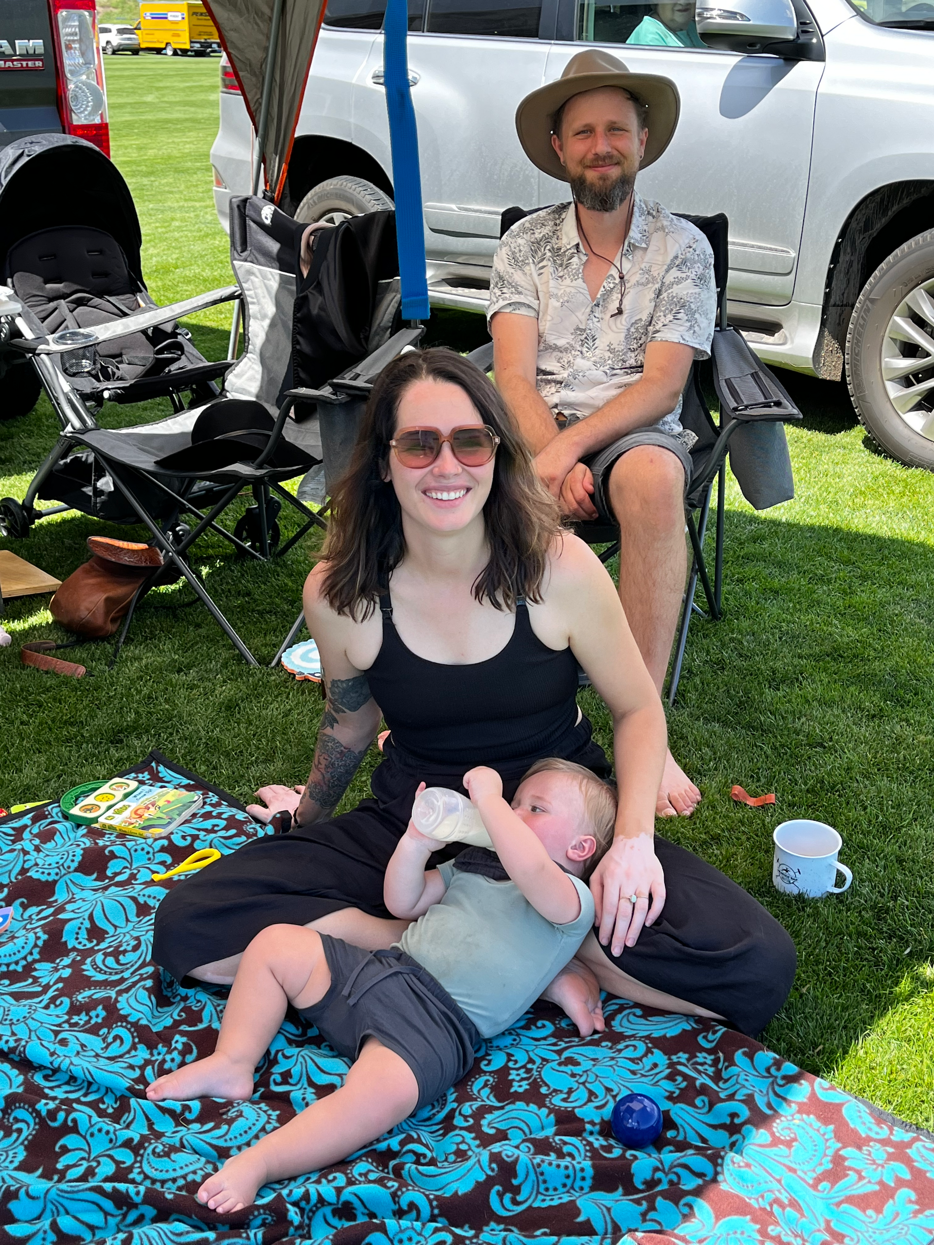 A woman is sitting on a blanket with a baby.