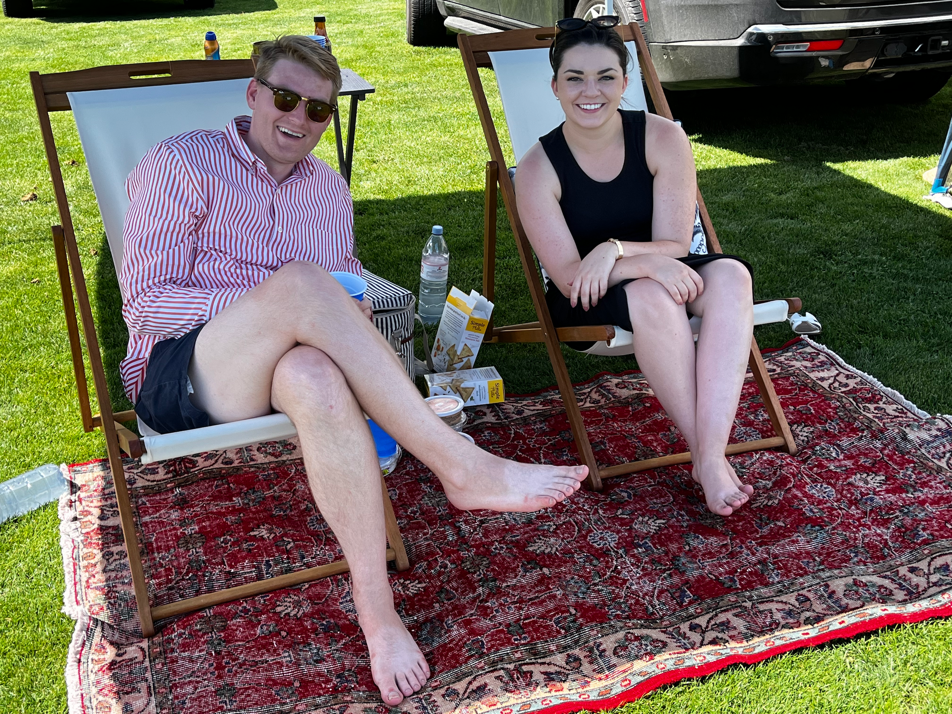 A man and a woman are sitting in lawn chairs on a rug.