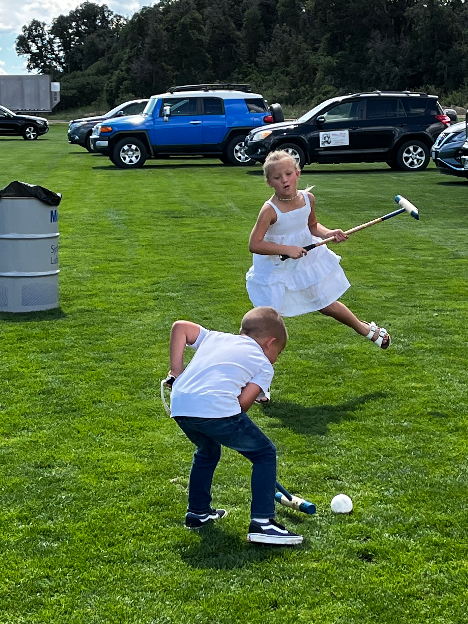A boy and a girl are playing polo in a field.