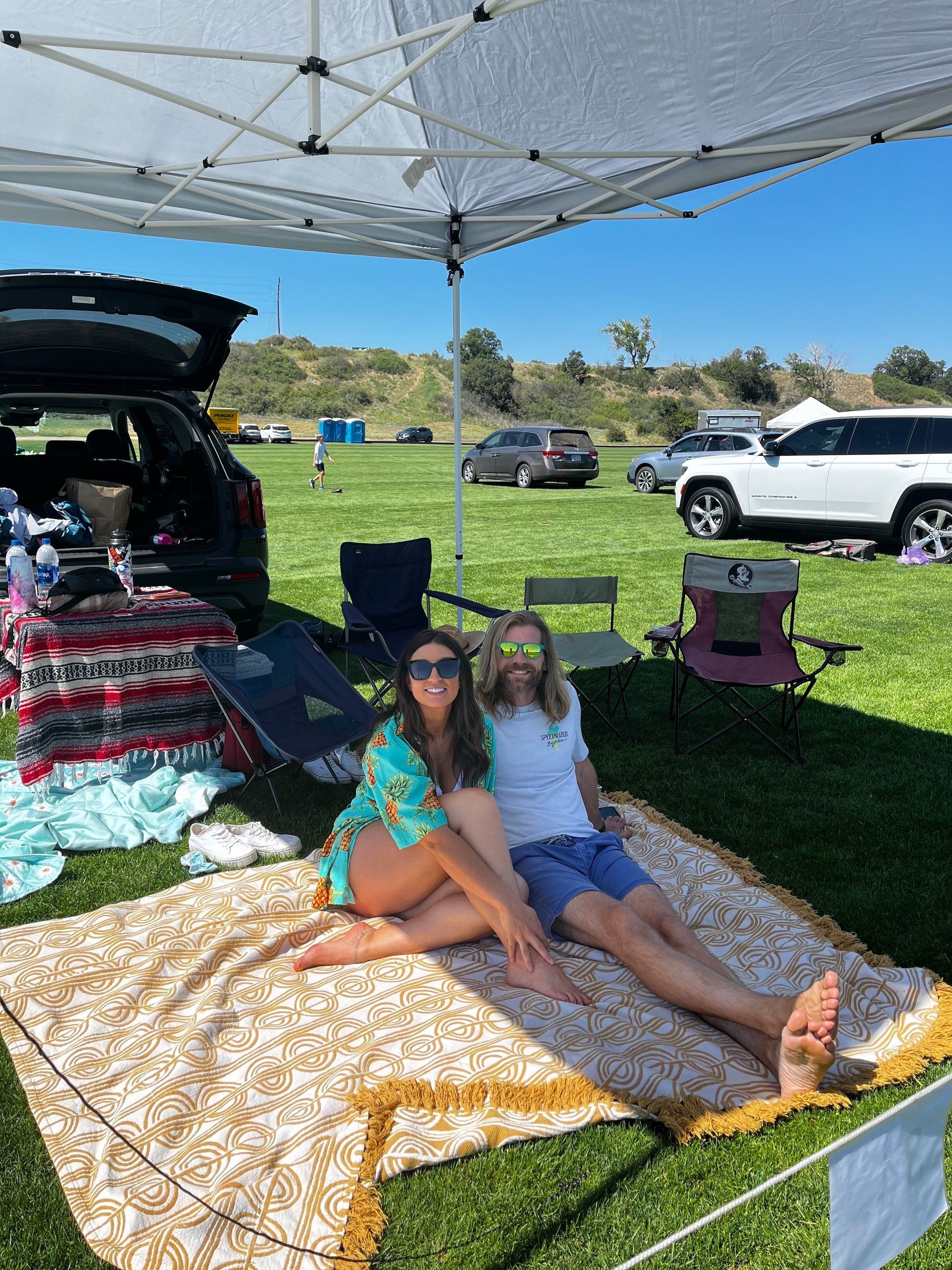 A man and a woman are sitting on a blanket under a tent.