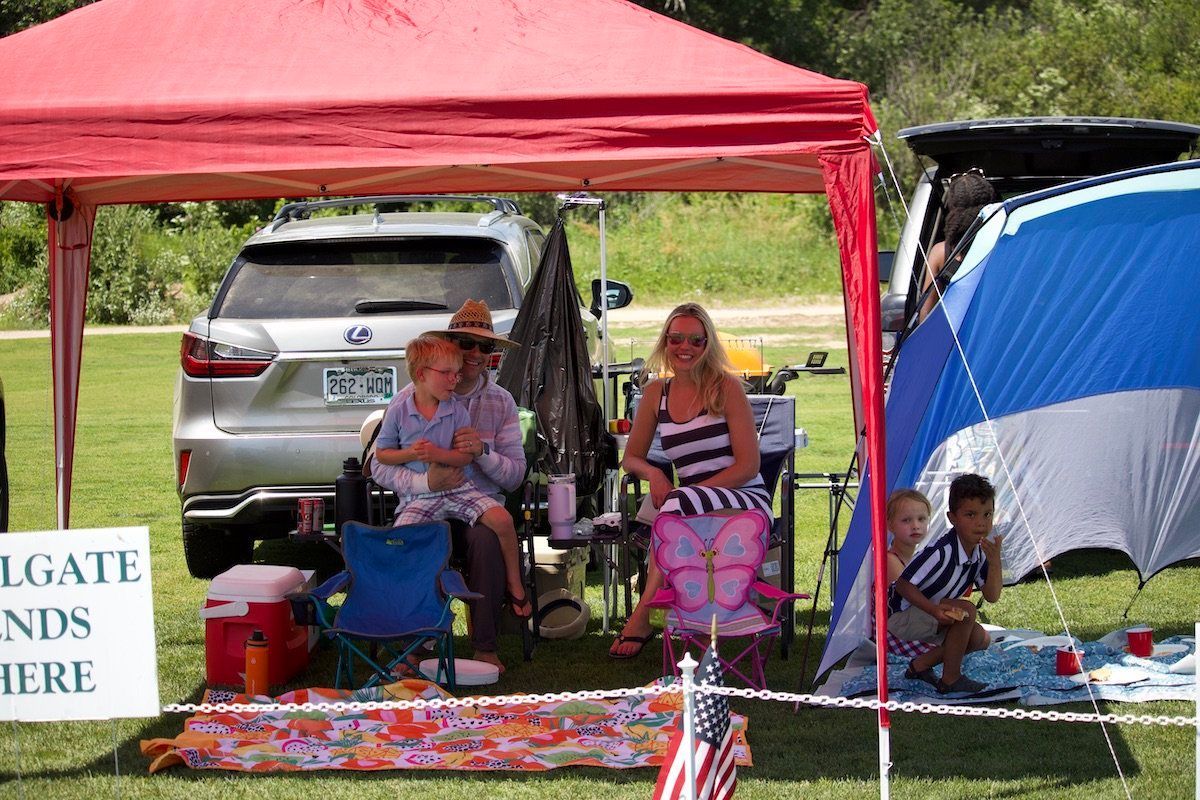A group of people sitting under a tent with a sign that says ' gate 's here '