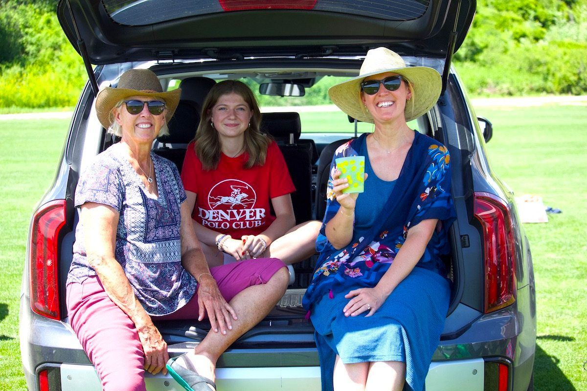 Three women are sitting in the back of a car.