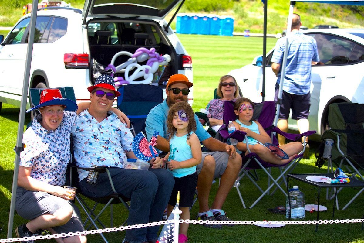 A group of people are sitting in chairs in front of a car.