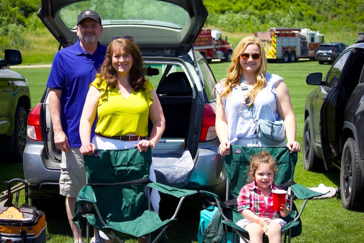 A family is posing for a picture in front of a car.