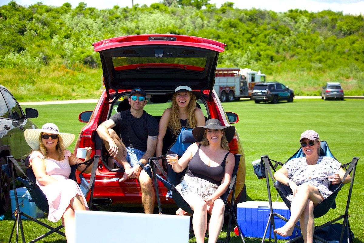 A group of people are sitting in the back of a red car.