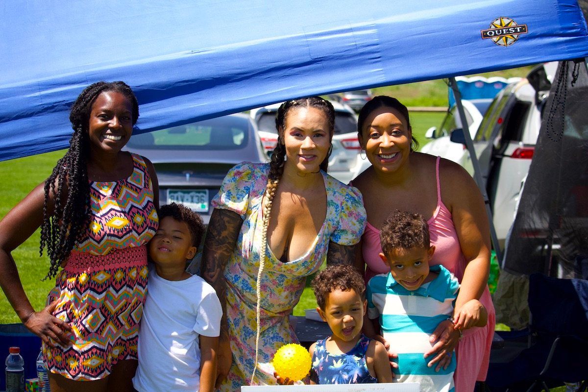 A group of women and children are posing for a picture under a tent.