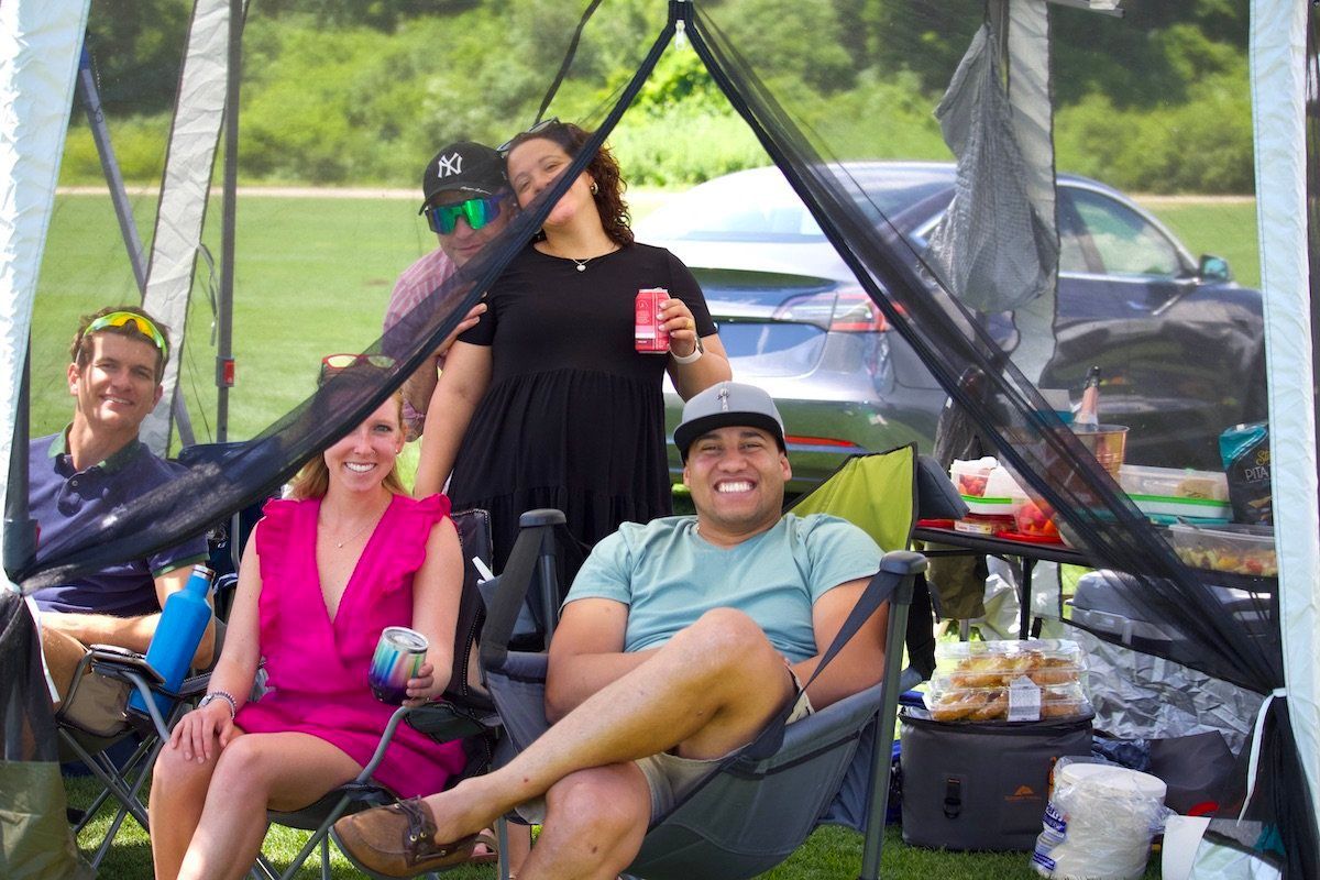 A group of people are sitting in chairs under a tent.