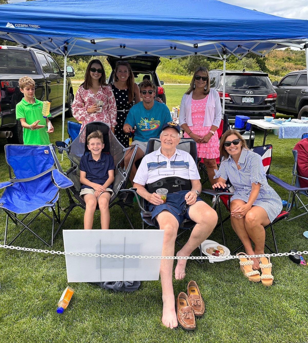 A group of people are sitting under a blue tent.