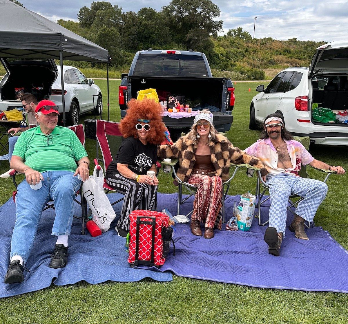 A group of people are sitting on a blanket in a field.