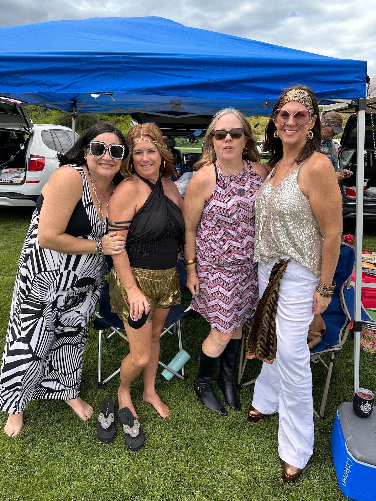 A group of women are posing for a picture under a blue tent.