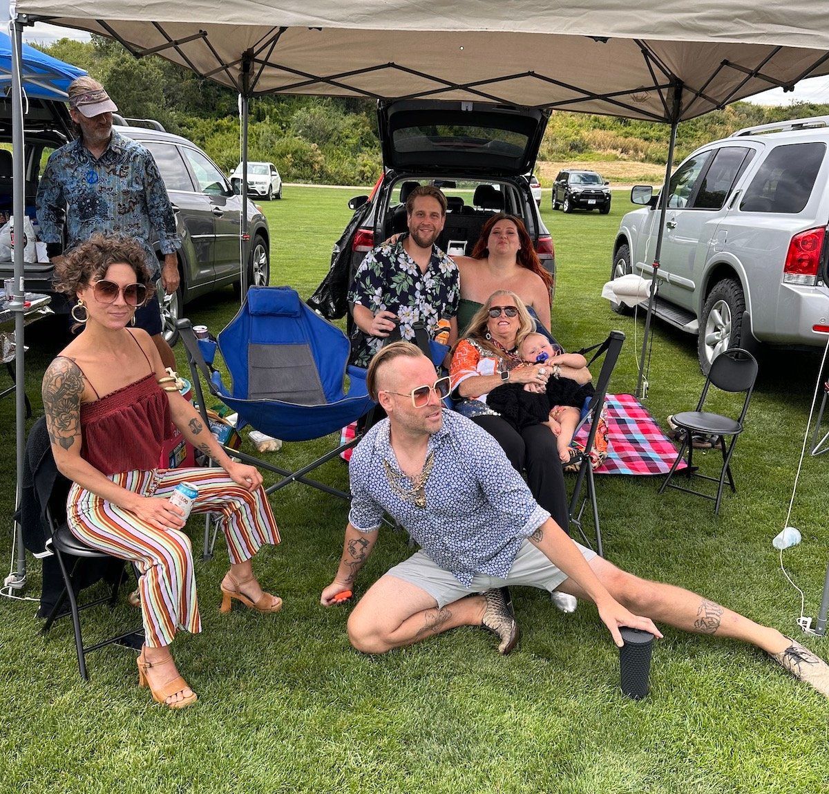 A group of people are sitting under a tent in a field.