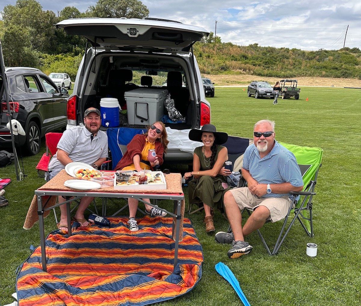 A group of people are sitting around a table in the back of a car.