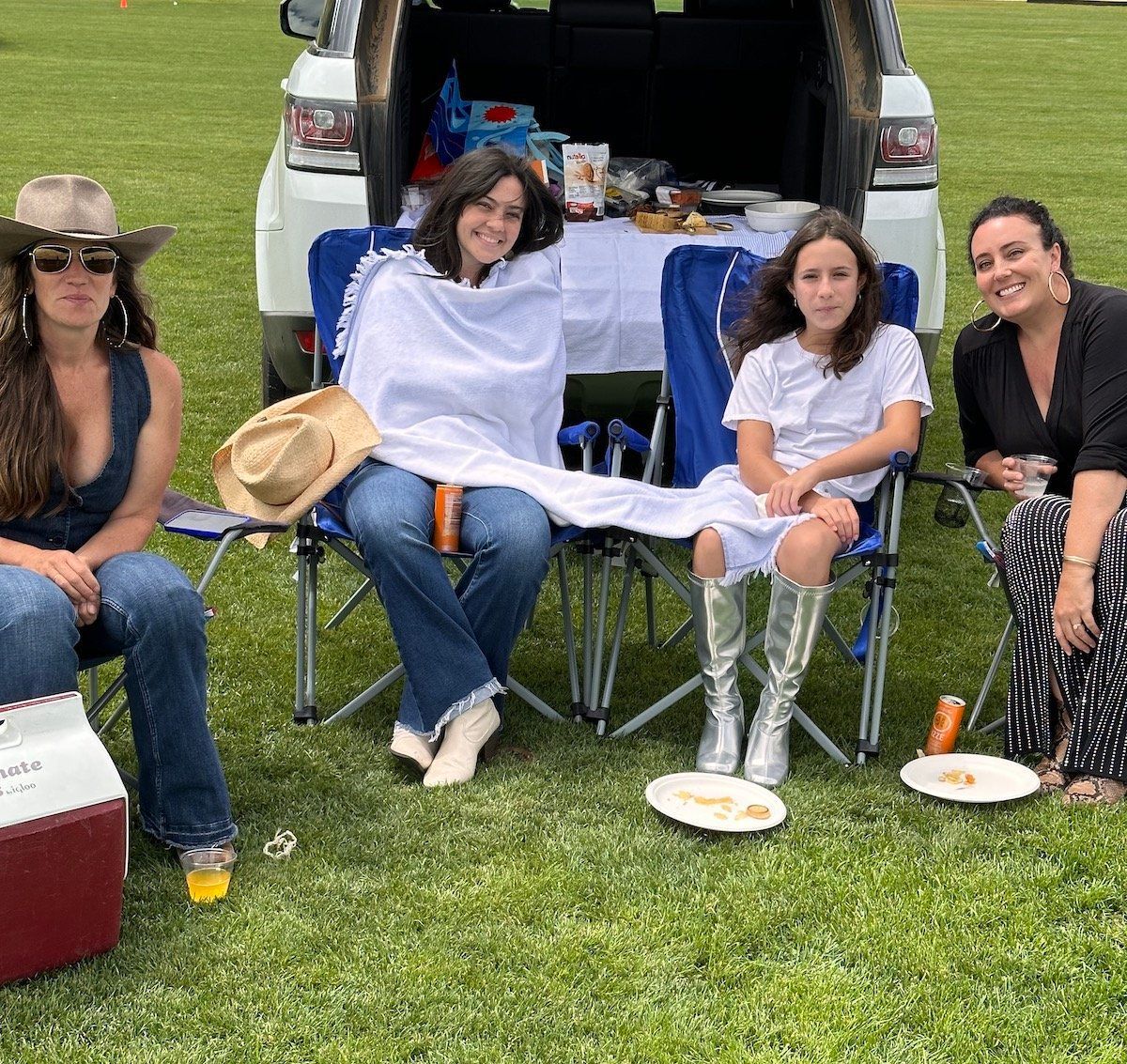 A group of women are sitting in chairs in front of a car