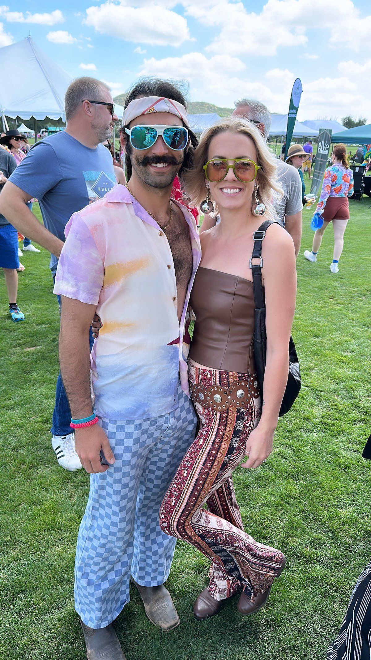 A man and a woman are posing for a picture in a field.