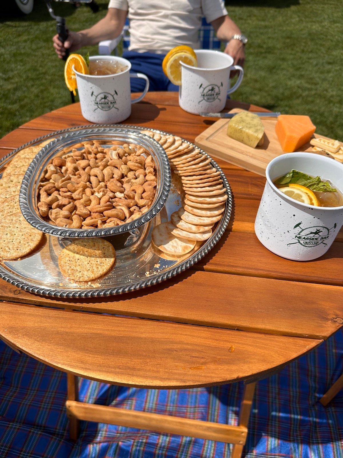 A wooden table topped with nuts , crackers , and a bowl of soup.