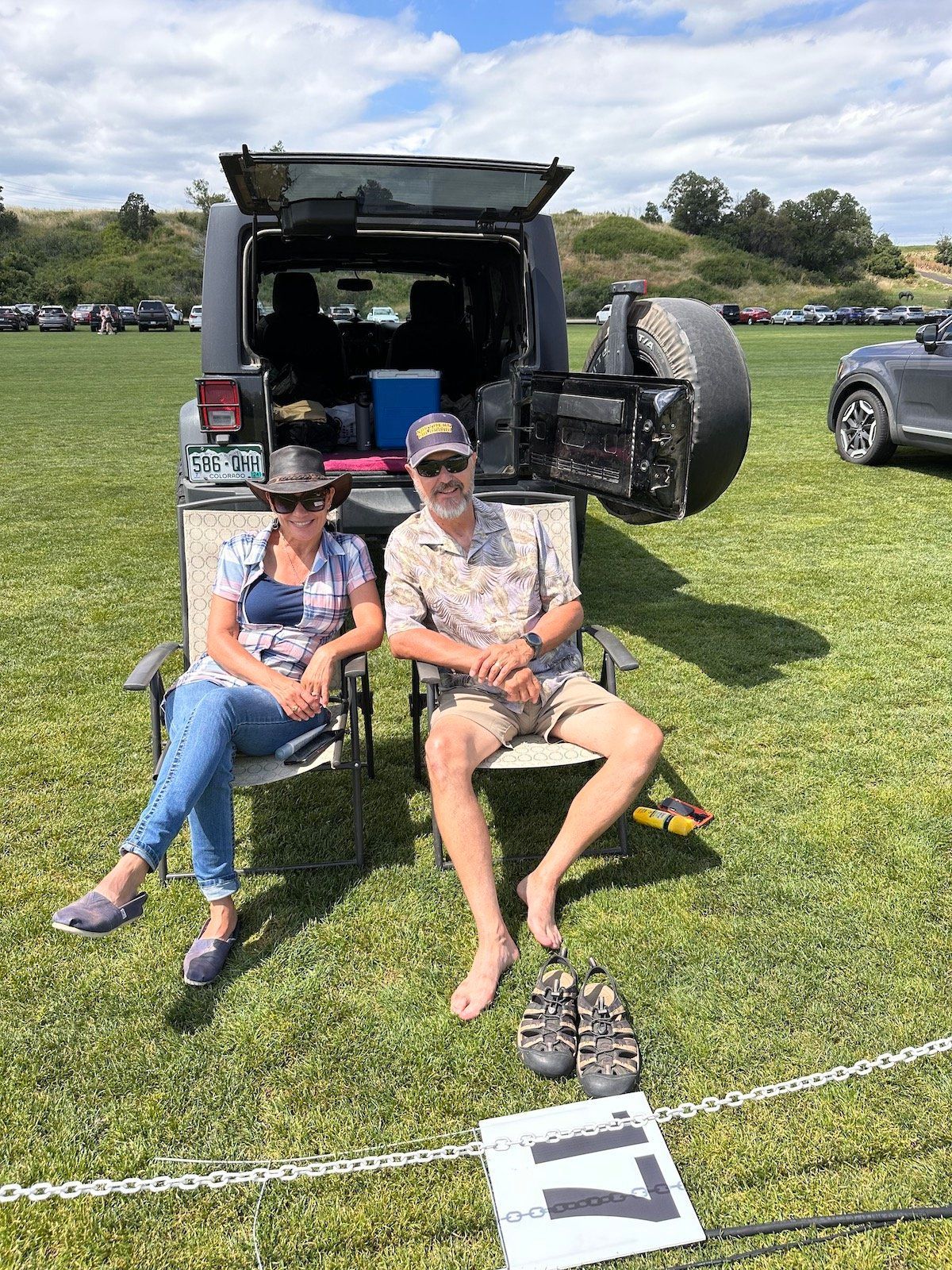 A man and a woman are sitting in chairs in front of a jeep.