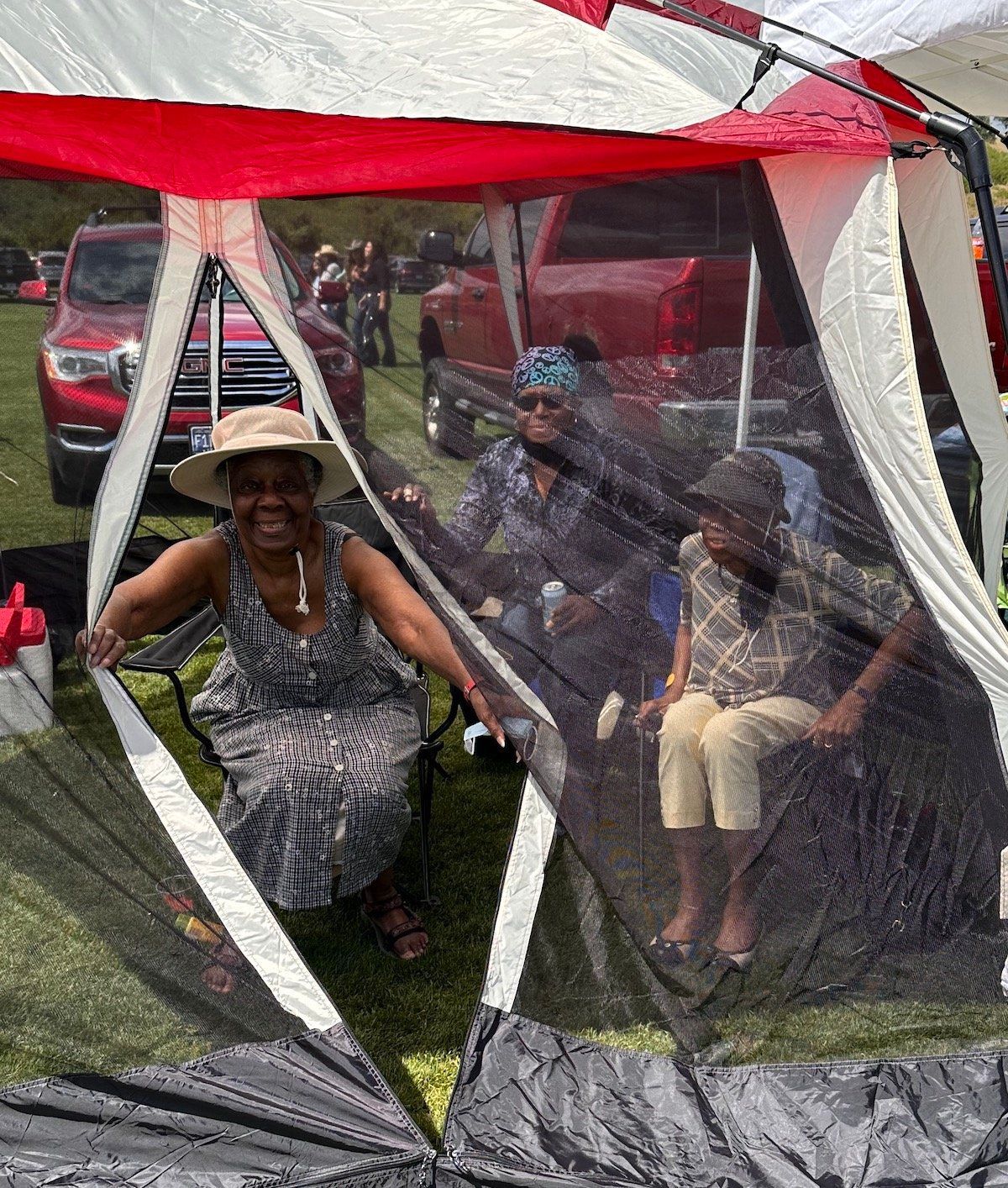 A woman is sitting in a tent with a mosquito net.