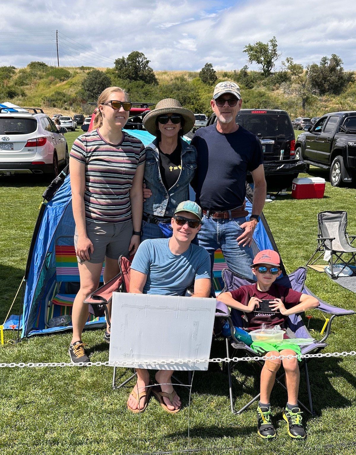 A family is posing for a picture in front of a tent in a field.