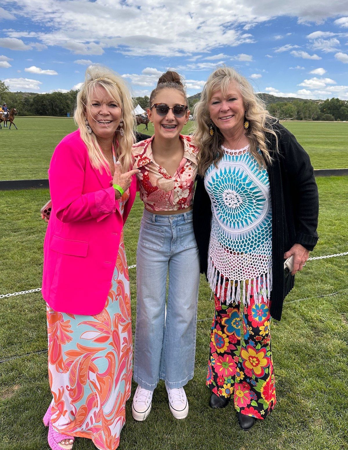 Three women are posing for a picture in a field.
