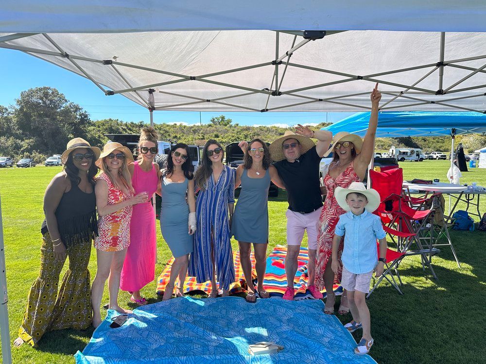 A group of people are standing under a tent in a field.
