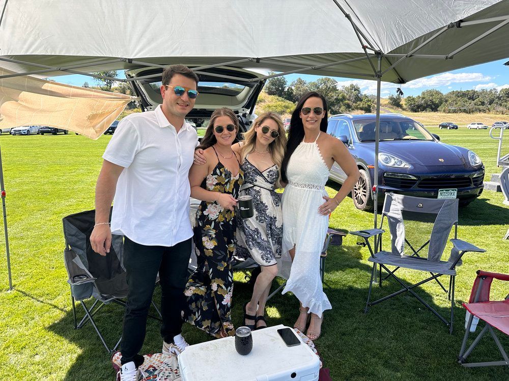 A group of people are standing under a tent in a field.