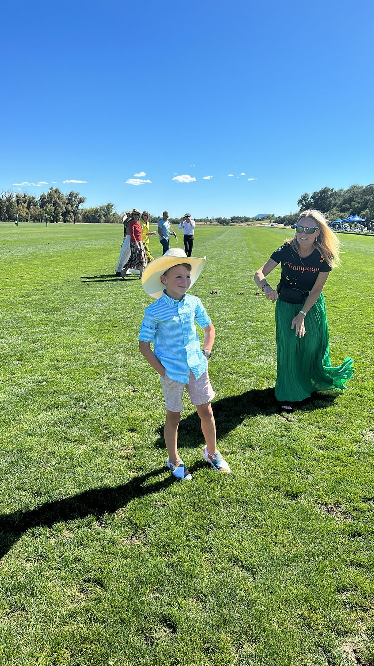A woman and a boy are standing in a grassy field.