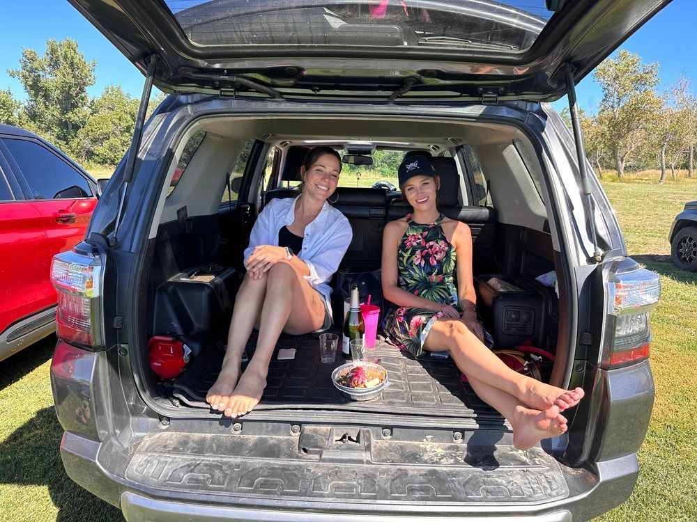 Two women are sitting in the back of a car.
