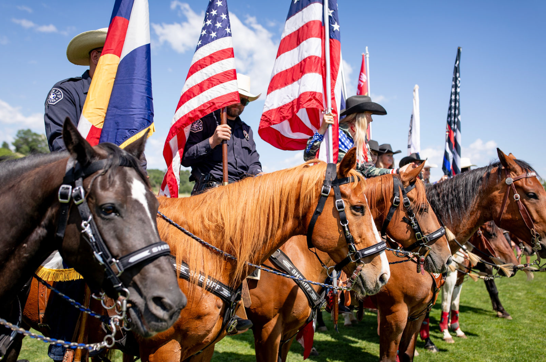 A group of people riding horses holding american flags.