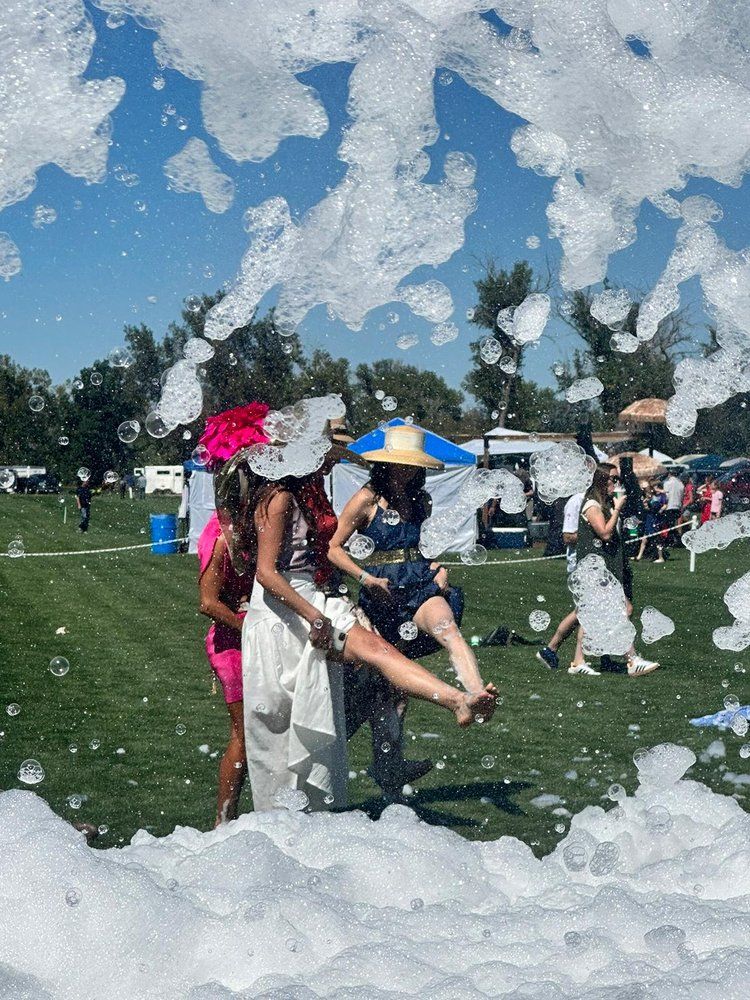 A group of people are standing in a field surrounded by foam.