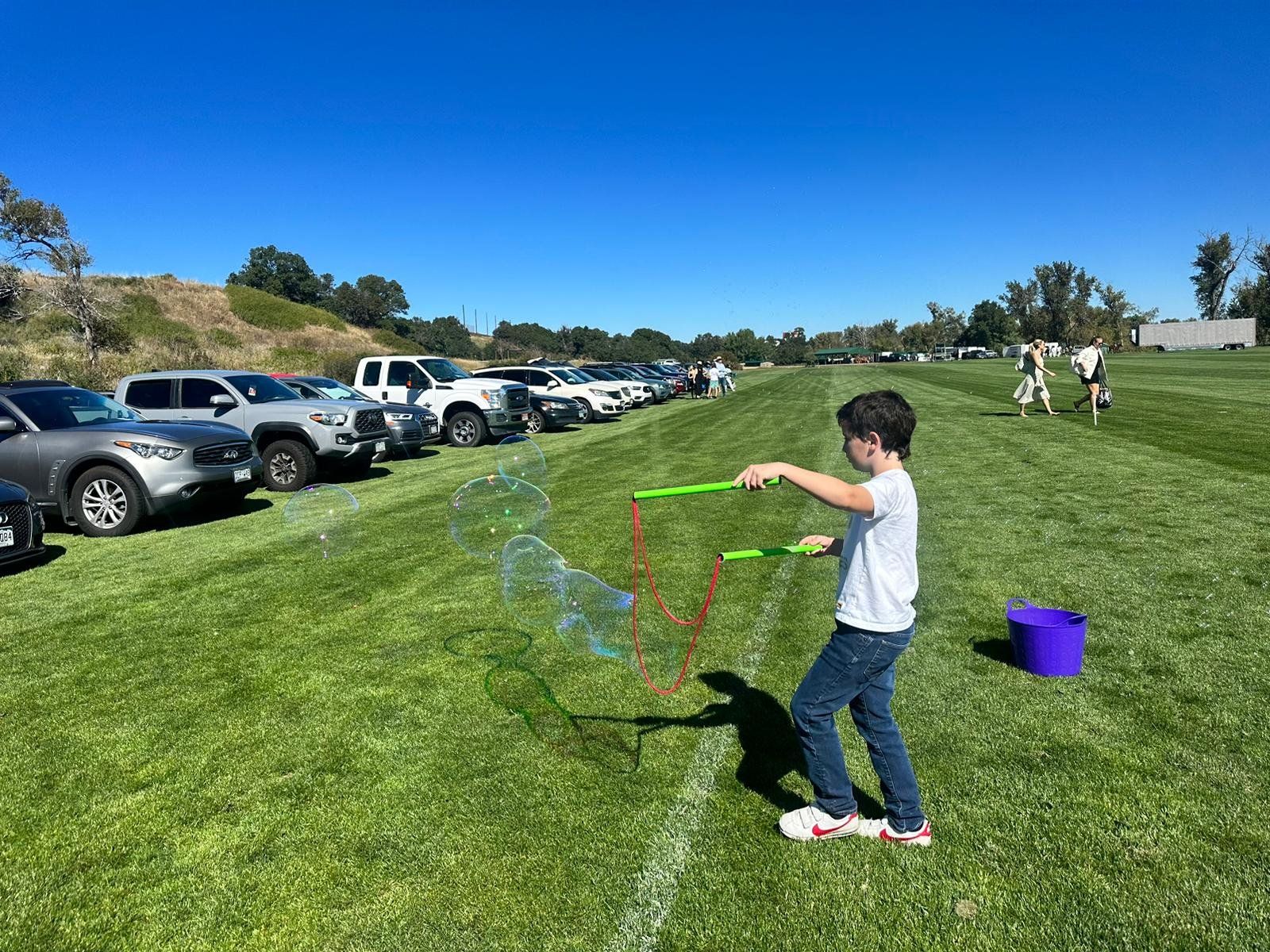 A young boy is blowing soap bubbles in a park.