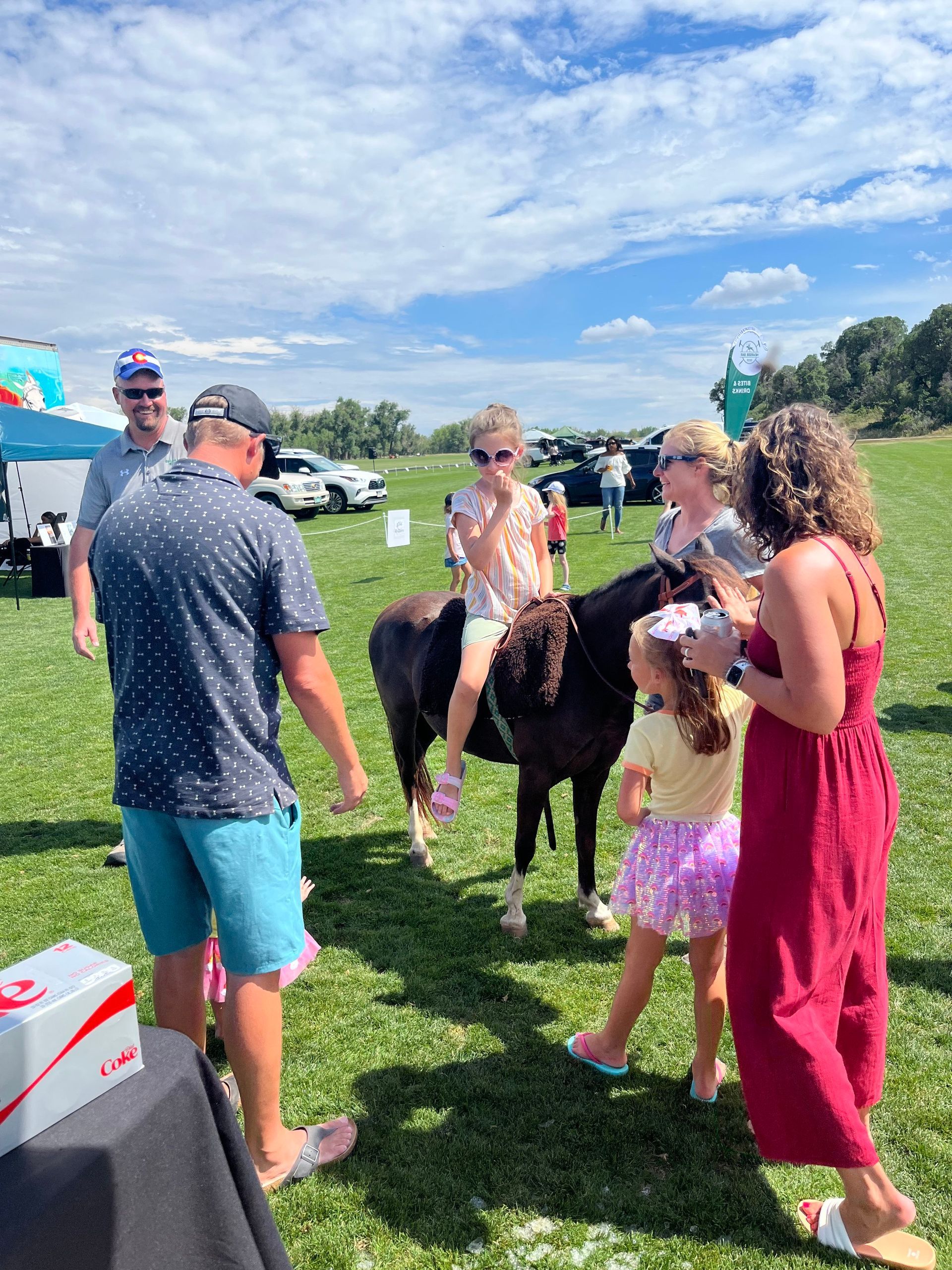 A group of people are standing around a pony in a field.