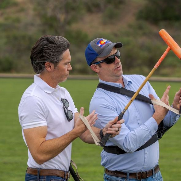 Two men are playing a game of polo on a lush green field