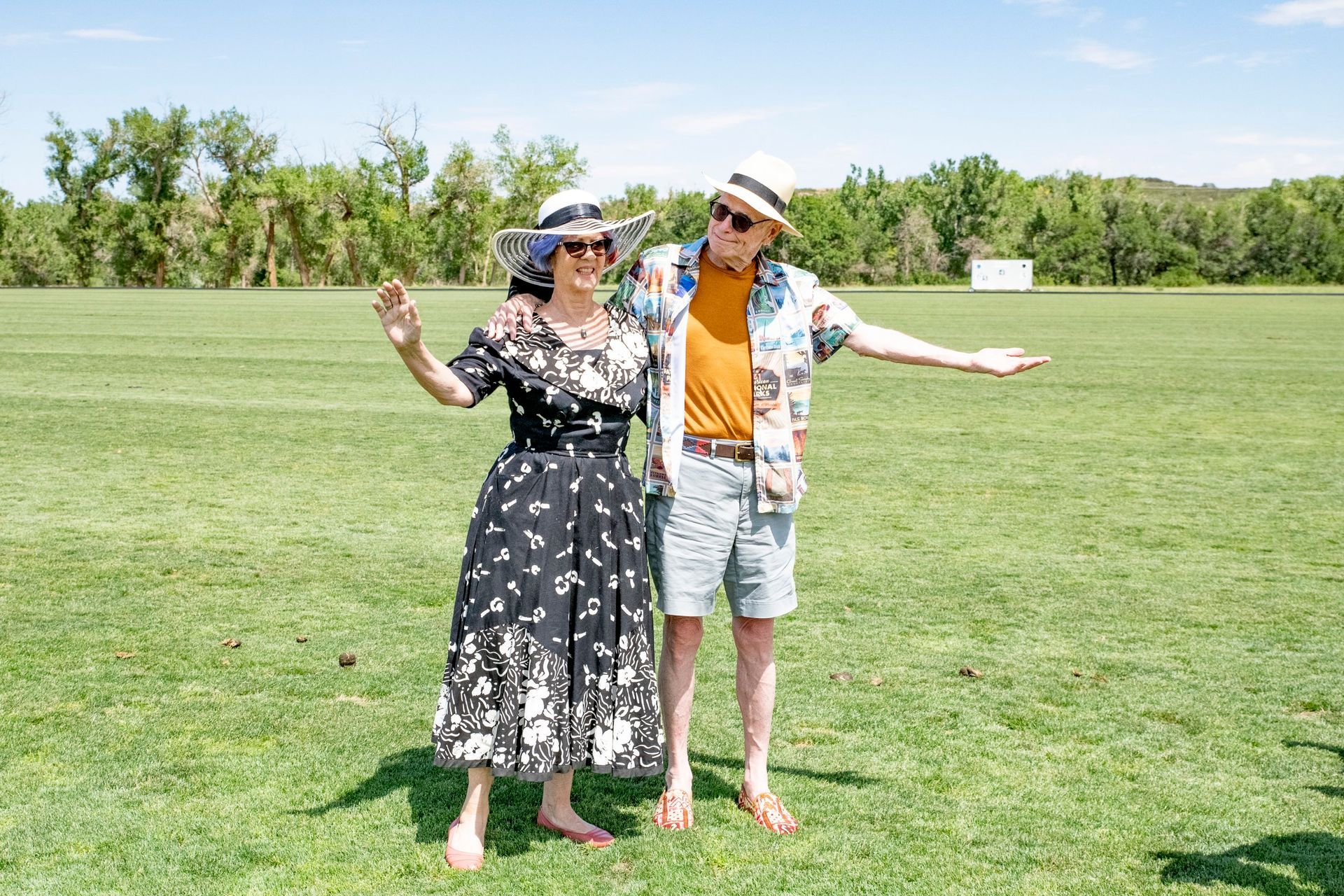 A man and a woman are standing in a grassy field.