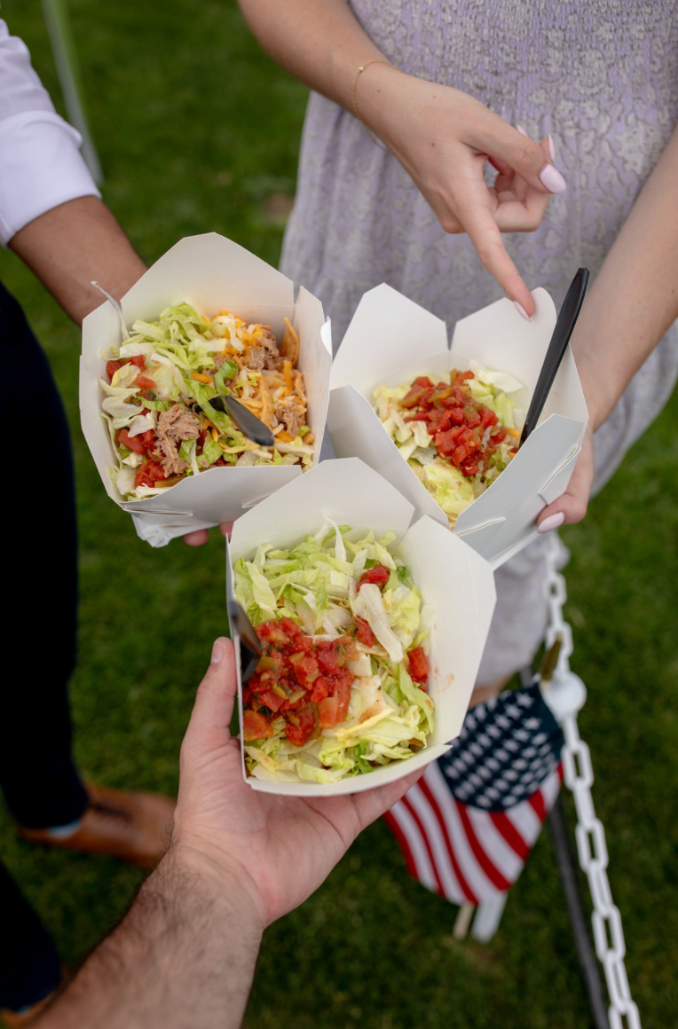 A group of people are holding containers of food in their hands.