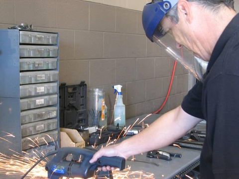 A man wearing a face shield is using a grinder