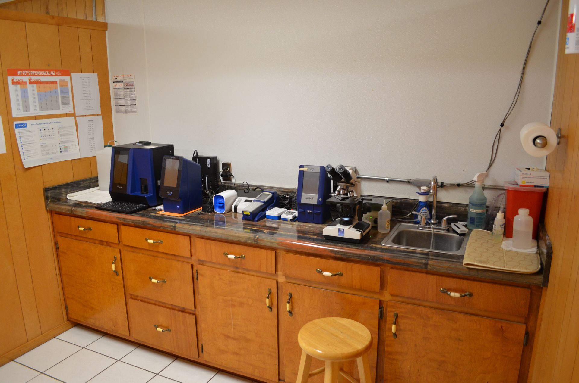 Laboratory with cabinets, sink, equipment, and a stool.