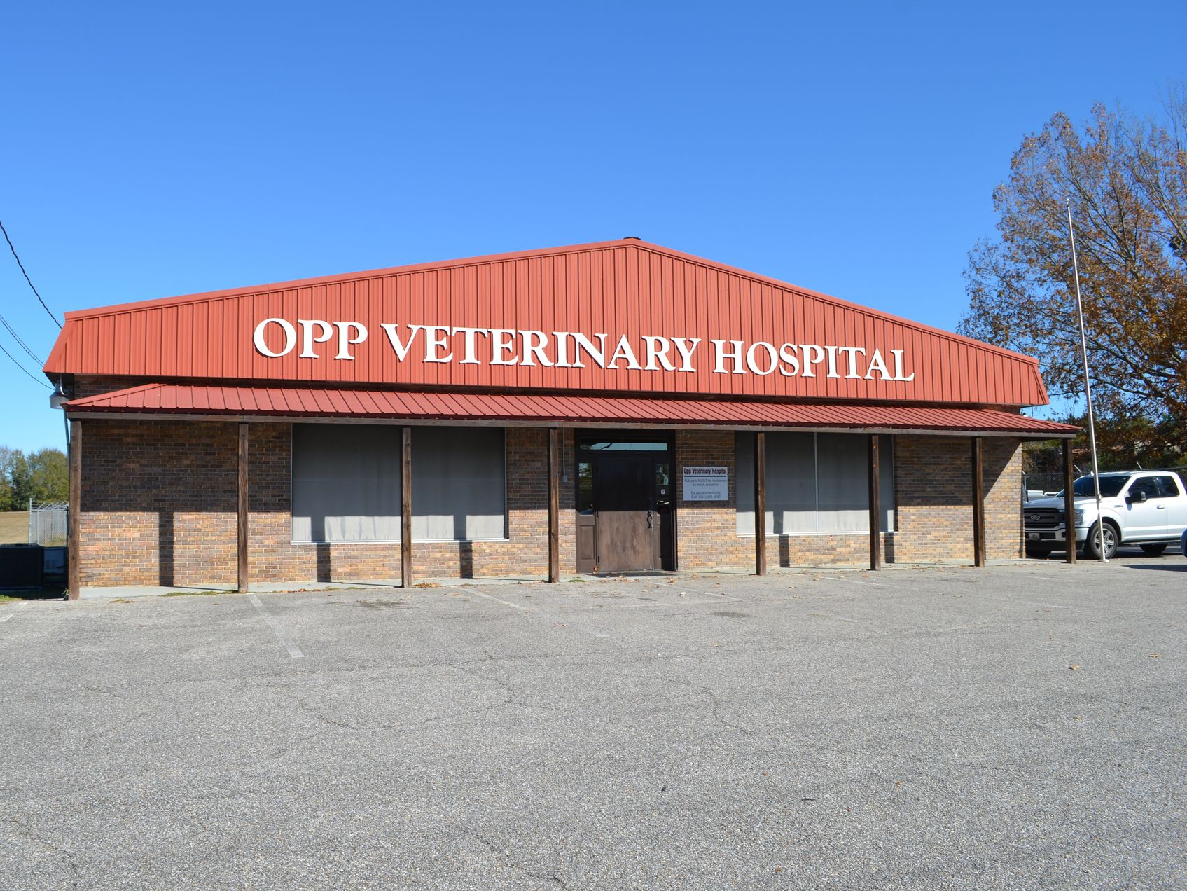 Opp Veterinary Hospital, red roof, brown brick building, blue sky, white truck parked in front.
