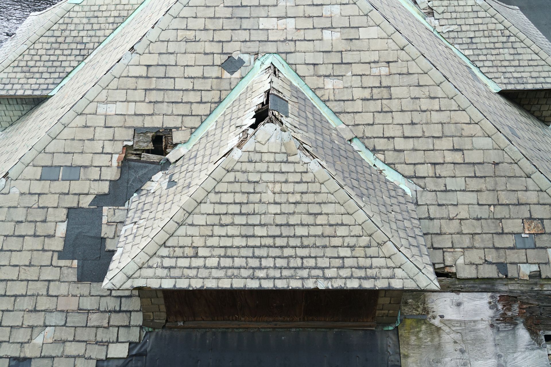 A damaged roof with missing shingles and visible sagging, indicating the need for replacement.