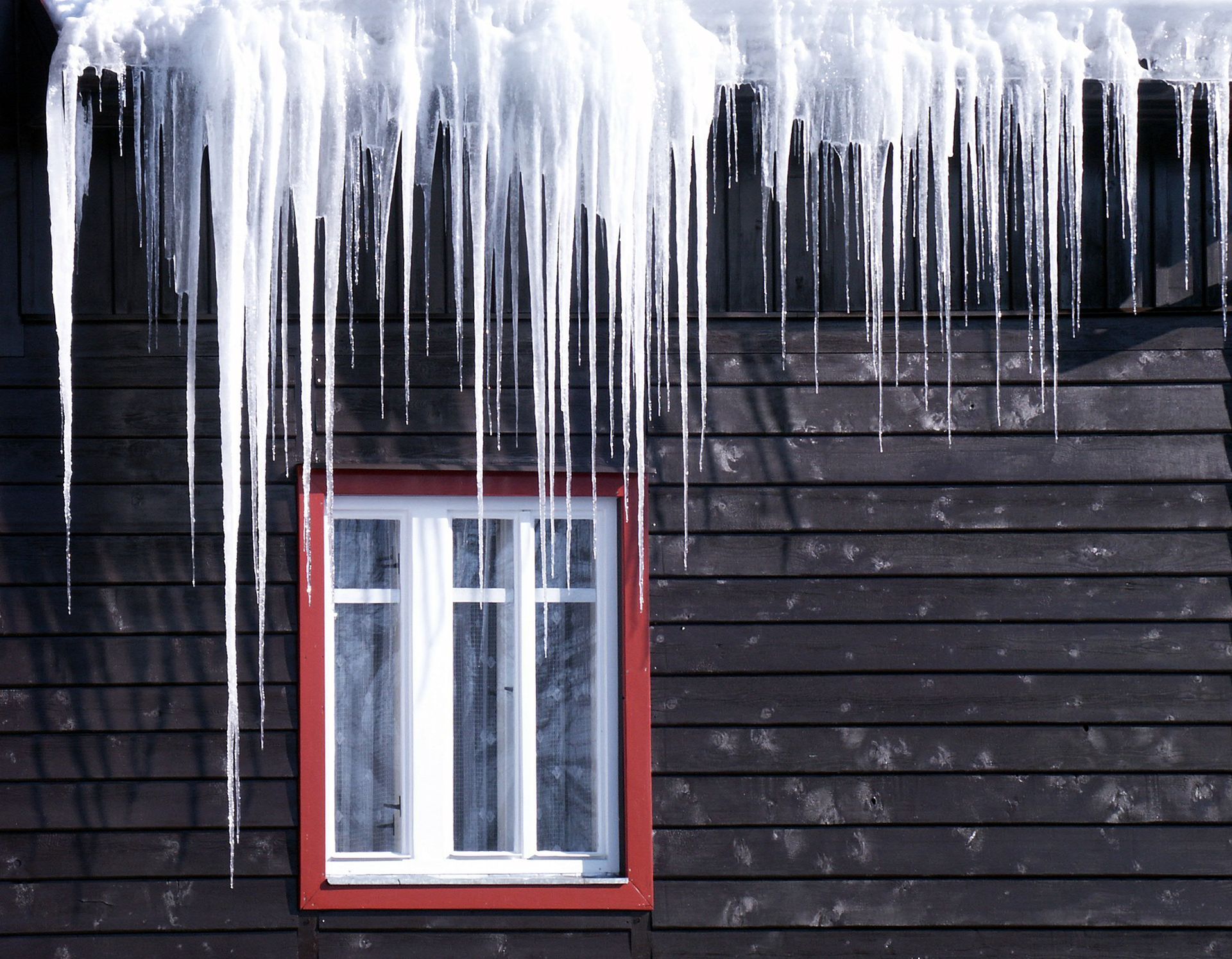 A snow-covered roof in Akron, Ohio, with visible damage and missing shingles after a winter storm.