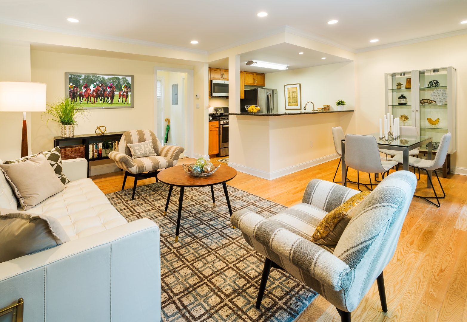 A living room with a couch , chairs , a table and a rug.