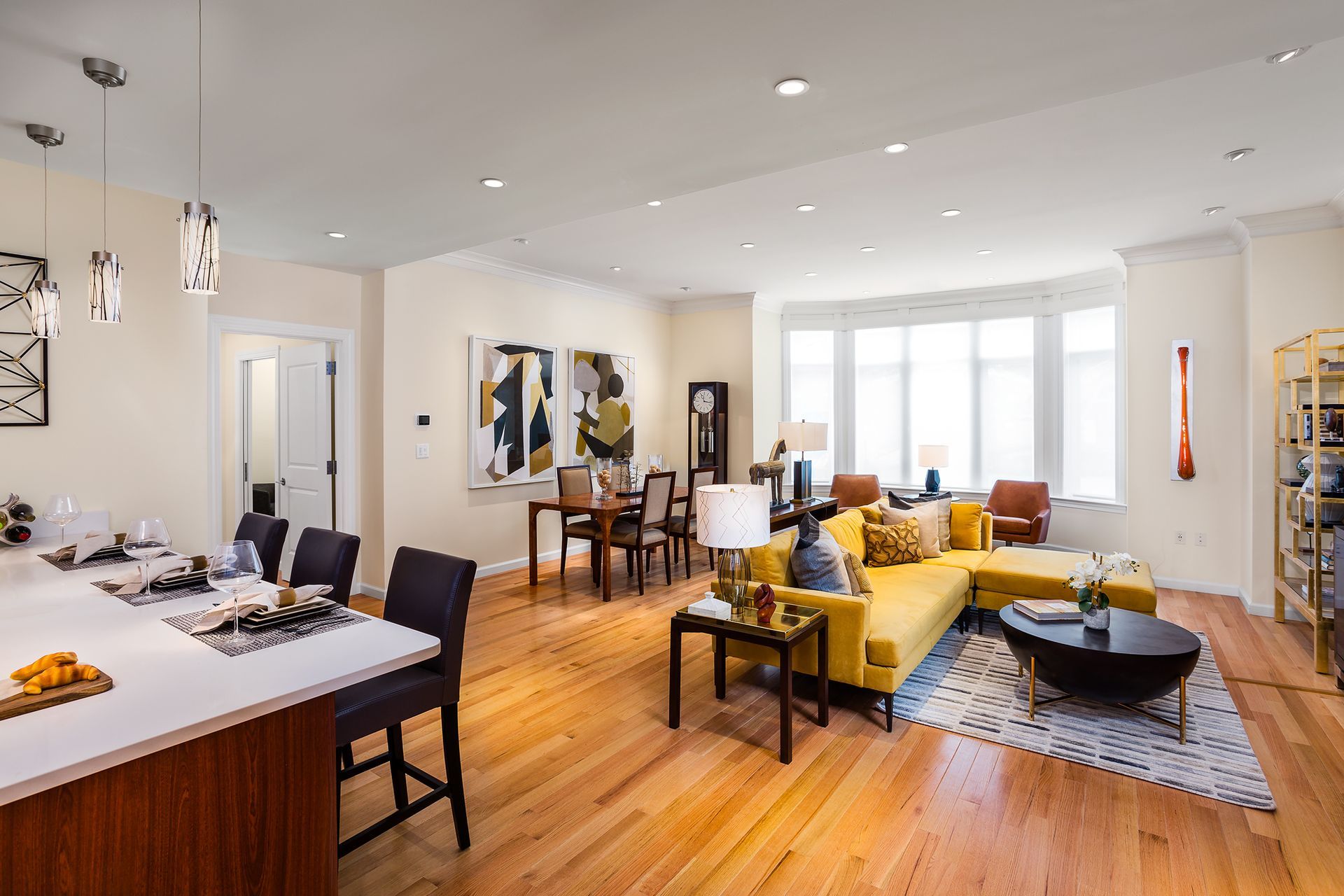 Open-concept living space with a kitchen island, dining table, and mustard-yellow sectional sofa.