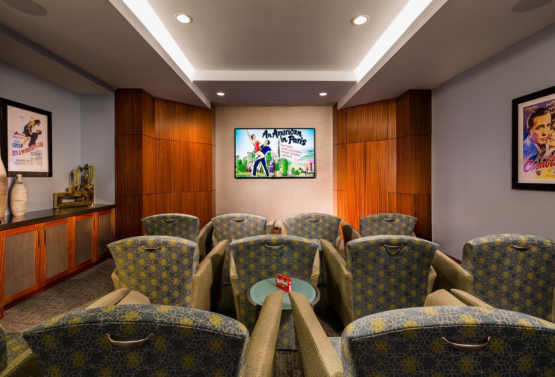 Home theater room with patterned chairs, large screen, and wooden accents.