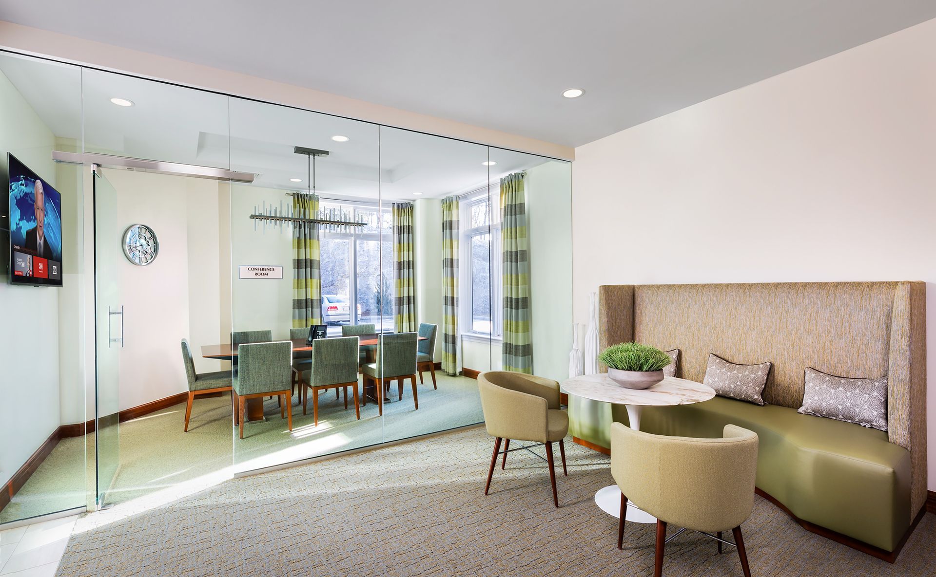 Modern meeting room with glass walls, table, chairs, and a small dining area.
