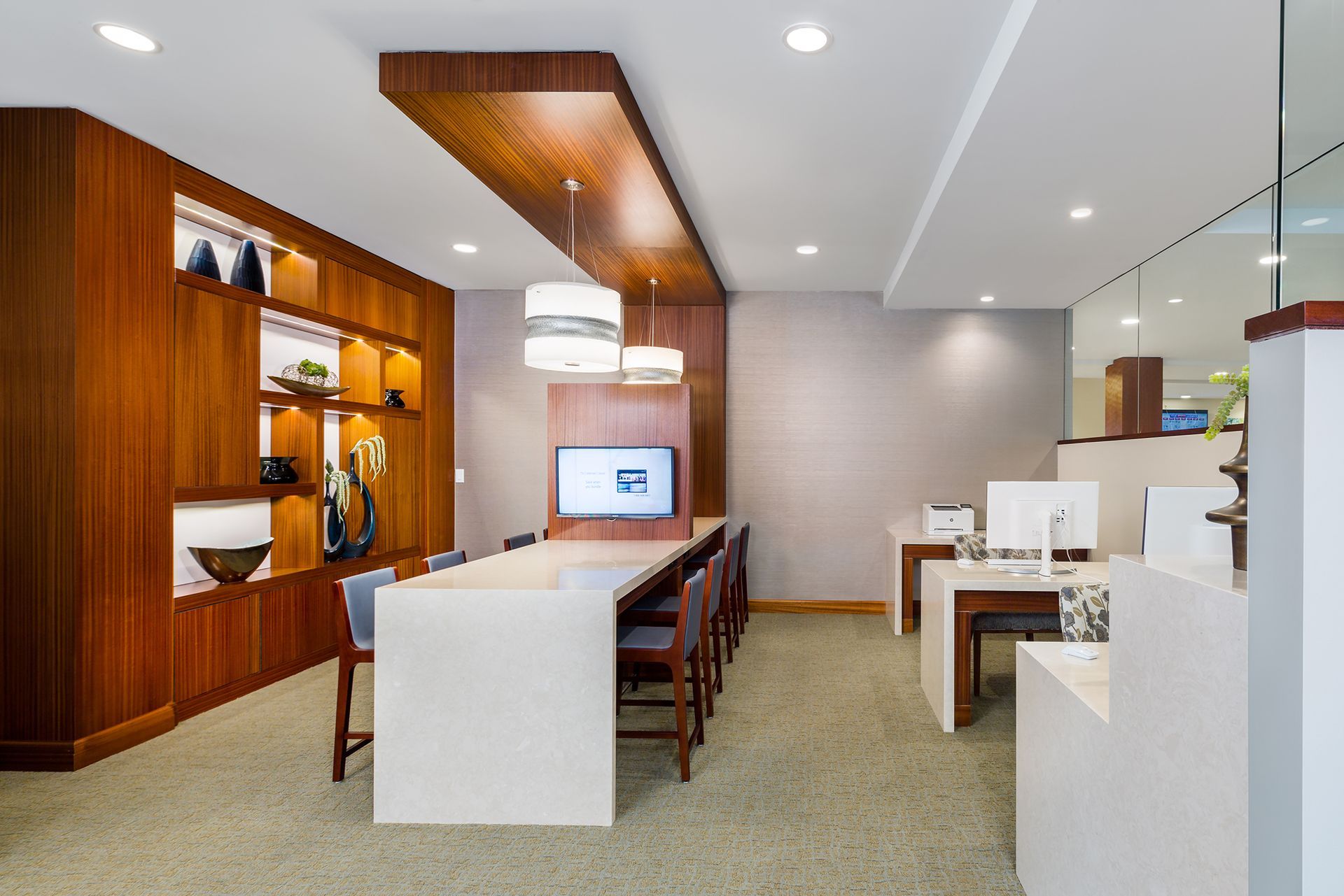 Modern hotel lobby with long table, wood paneling, and built-in shelving.