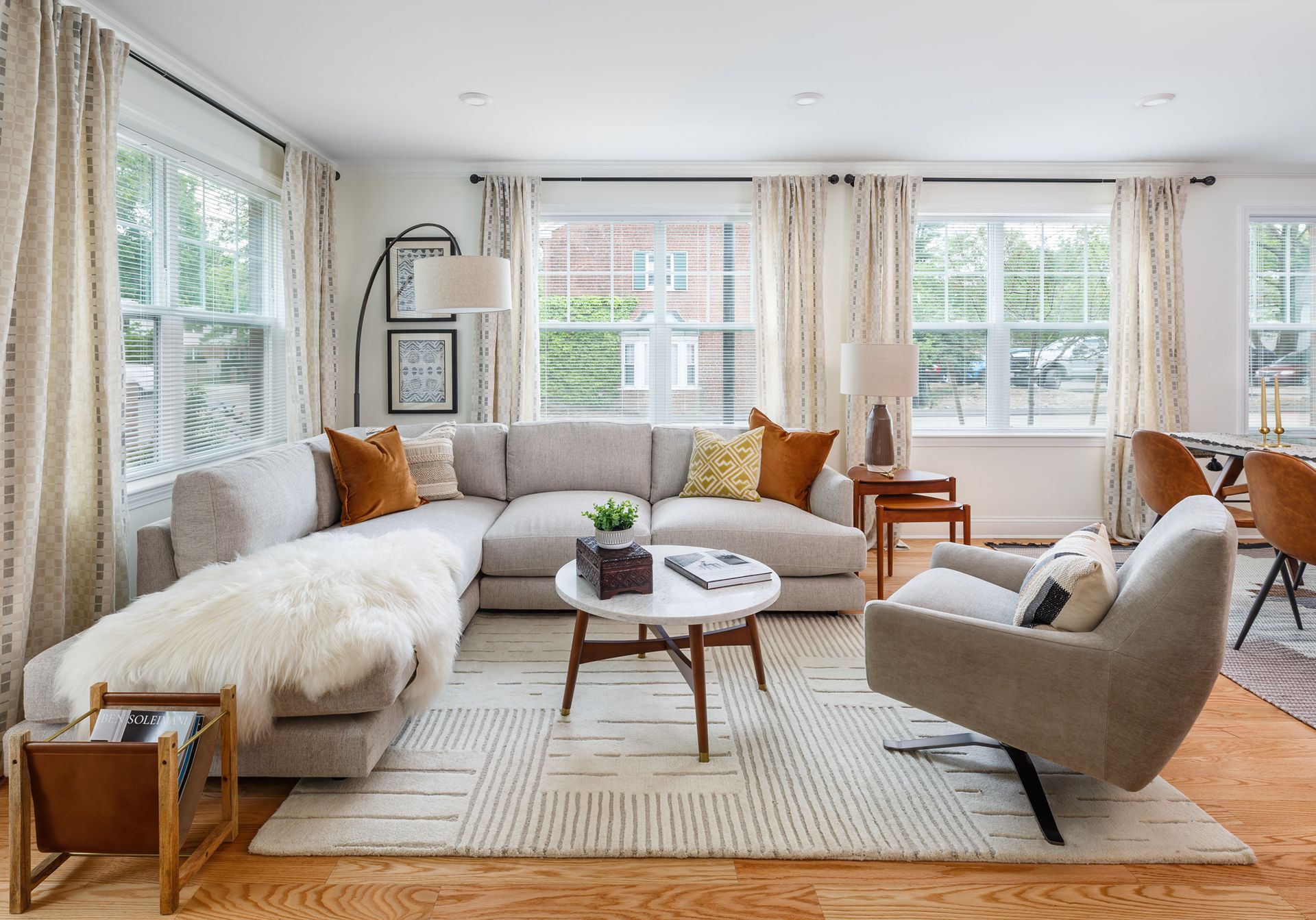 Living room with large sectional, armchair, coffee table, rug, and windows with curtains.