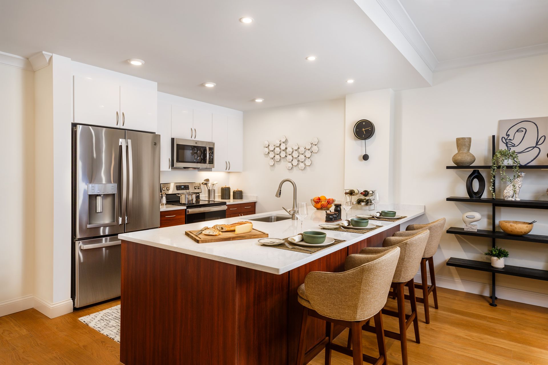 Modern kitchen with island, stainless steel appliances, wood cabinets, and bar stools.